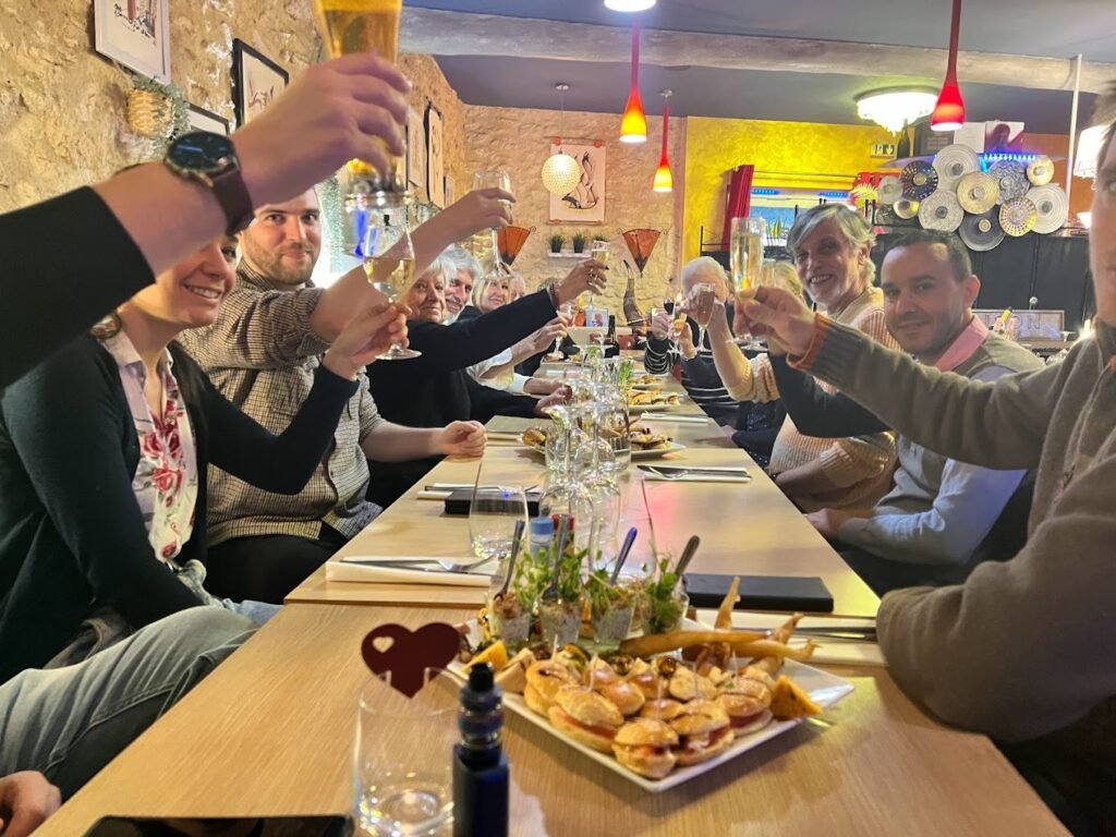 Dîner convivial entre amis au restaurant Ôazar à Cavaillon, où des toasts sont portés autour d'une table garnie de délicieuses spécialités marocaines.