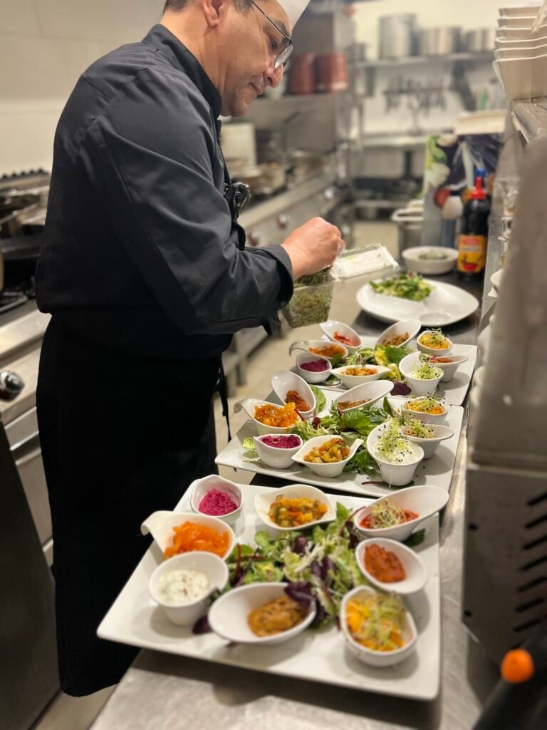 Chef Salah du restaurant Ôazar à Cavaillon en train de préparer des assiettes de mezzes dans la cuisine.