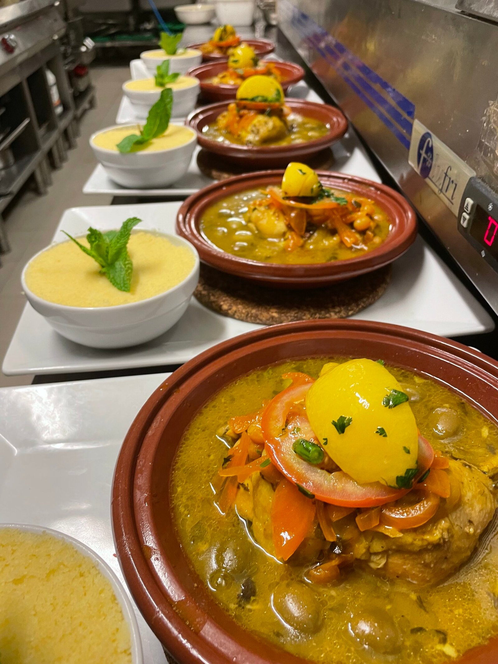 Tajines de poulet servis avec semoule de couscous, garnis de légumes et de citron confit, prêts à être servis au restaurant Ôazar.