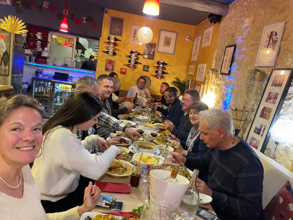 Un groupe de collègues partage un repas d'entreprise convivial au restaurant Ôazar à Cavaillon, savourant des plats marocains dans une ambiance chaleureuse et détendue comme le couscous et boivent du vin marocain.