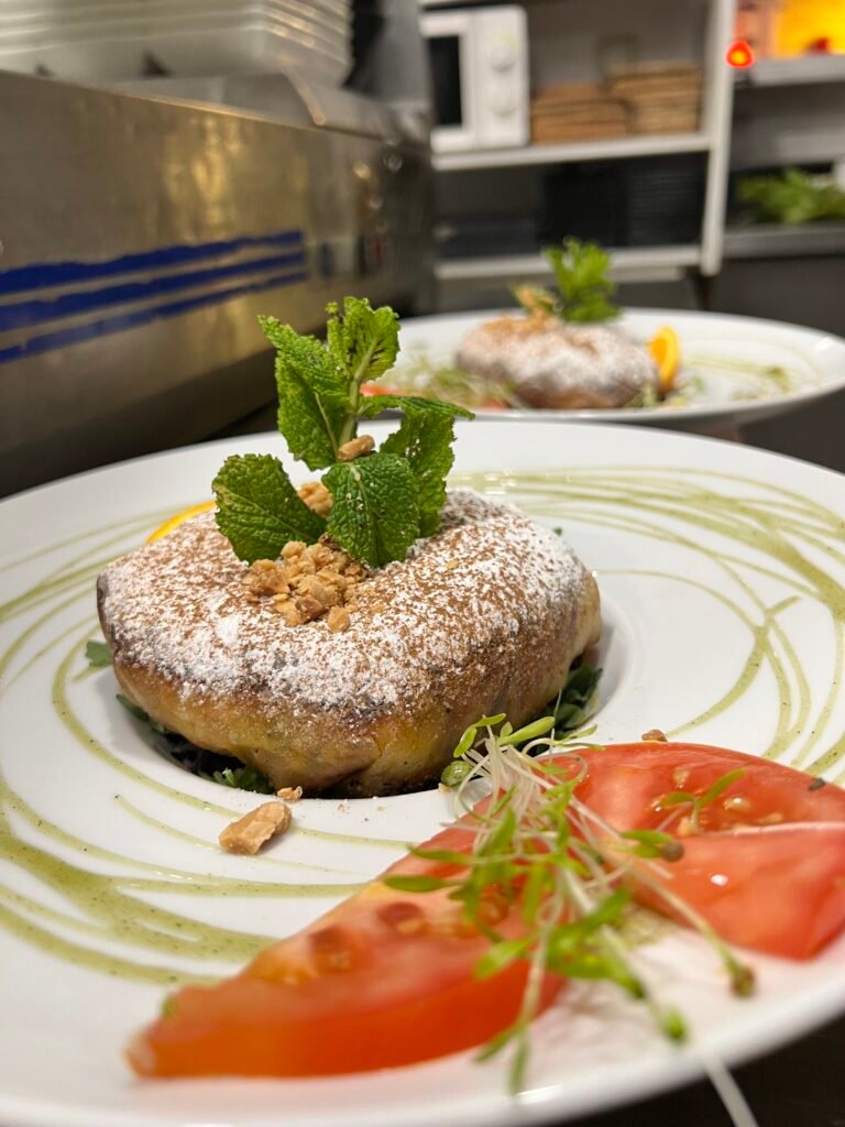 Plat de pastilla dorée garnie de menthe fraîche et de légumes, servi dans une assiette élégante avec une présentation raffinée au restaurant Ôazar à Cavaillon.