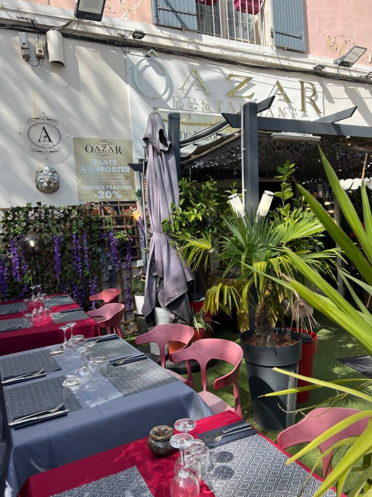 Entrée et terrasse du restaurant Ôazar à Cavaillon, avec des tables joliment dressées pour accueillir les clients dans une ambiance conviviale et verdoyante.